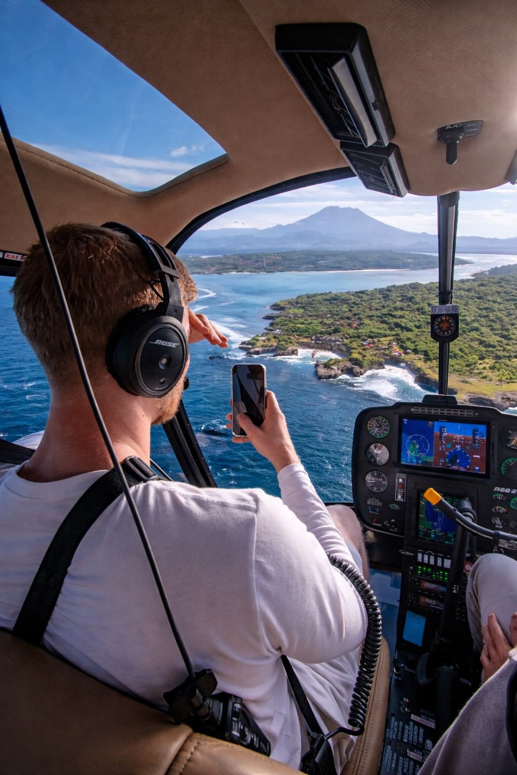 Passenger photographing Nusa Lembongan and Mount Agung from the helicopter cabin